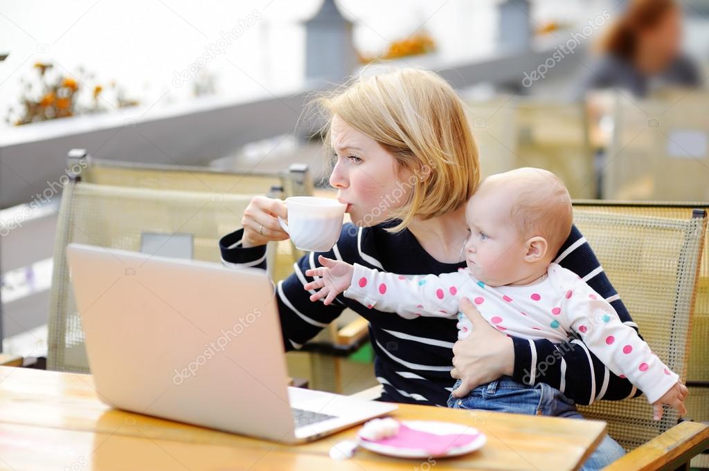 Tired young mother holding 6-month daughter and drinking coffee