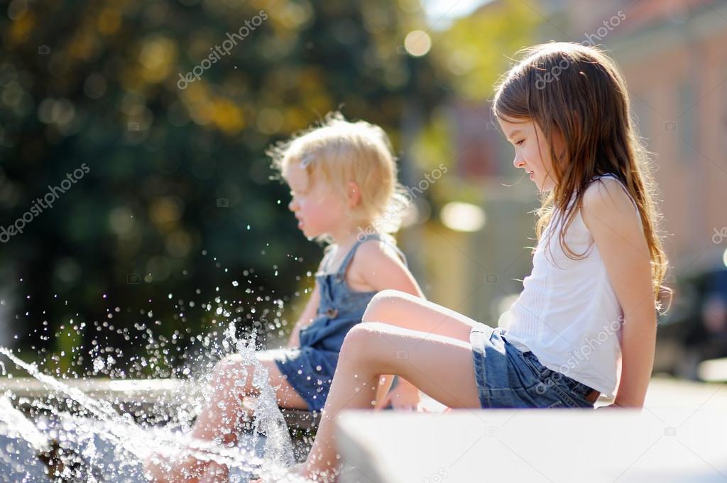 Little sisters having fun in a fountain 