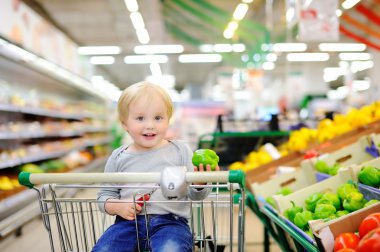 Bir süpermarkette alışveriş sepeti oturuyor ve yürümeye başlayan çocuk