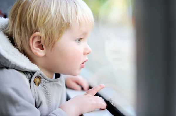 Petit garçon regardant par la fenêtre du train ou du tram — Photo