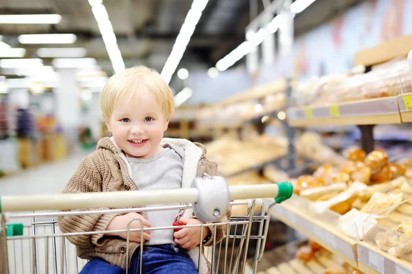 Bambino seduto nel carrello della spesa nel supermercato — Foto Stock