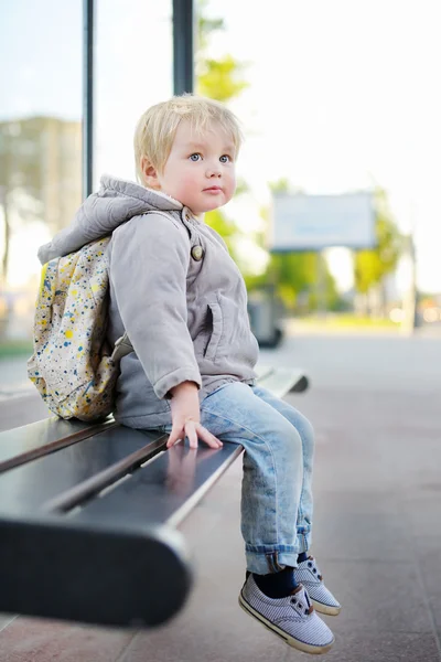 Toddler chłopiec siedzi na ławce na przystanek autobusowy — Zdjęcie stockowe