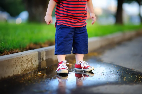 Bir su birikintisine ayakta yürümeye başlayan çocuk — Stok fotoğraf