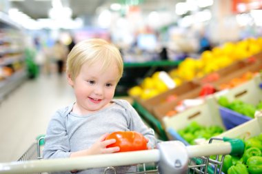 Bir süpermarkette alışveriş sepeti oturuyor ve yürümeye başlayan çocuk