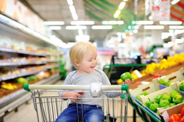 Bir süpermarkette alışveriş sepeti oturuyor ve yürümeye başlayan çocuk