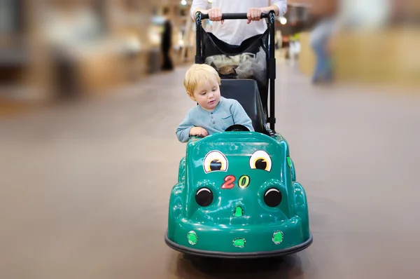 Menino sentado no carrinho de compras feito como carro de brinquedo — Fotografia de Stock