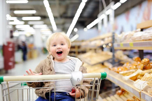 Tddler boy sitzt im Einkaufswagen in einem Supermarkt — Stockfoto