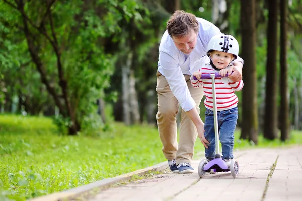 Vater zeigt seinem kleinen Sohn, wie man einen Roller fährt — Stockfoto