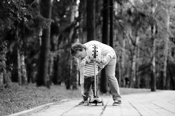 Padre de mediana edad mostrando a su hijo pequeño cómo montar en un scooter —  Fotos de Stock