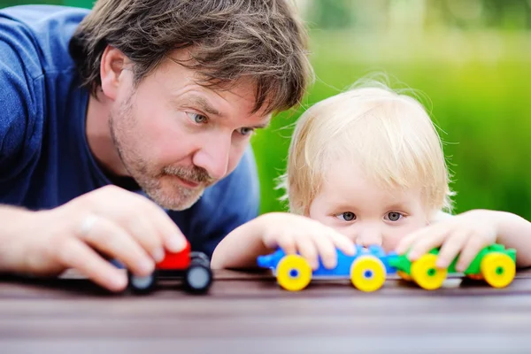 Vader met zijn peuter zoon spelen met speelgoed treinen — Stockfoto