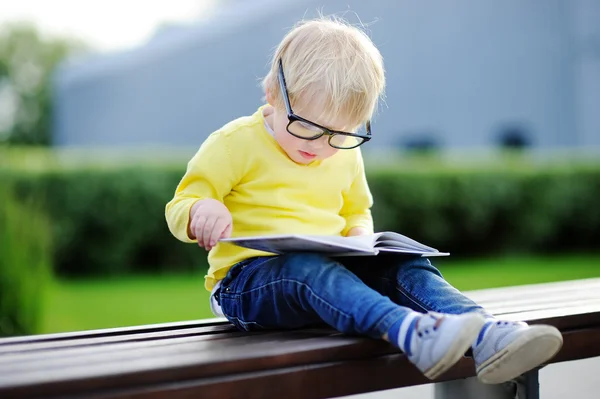 Schattig peuter jongen lezen van een boek buiten — Stockfoto