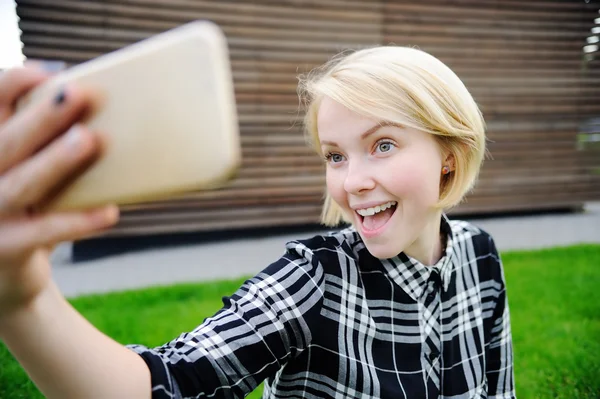Молодая женщина делает автопортрет со смартфоном — стоковое фото