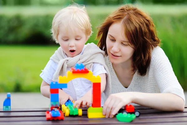 Молода жінка з маленьким сином грає з пластиковими блоками — стокове фото