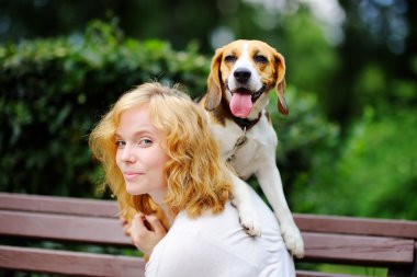 Genç kadın parkta Beagle köpek ile oynarken