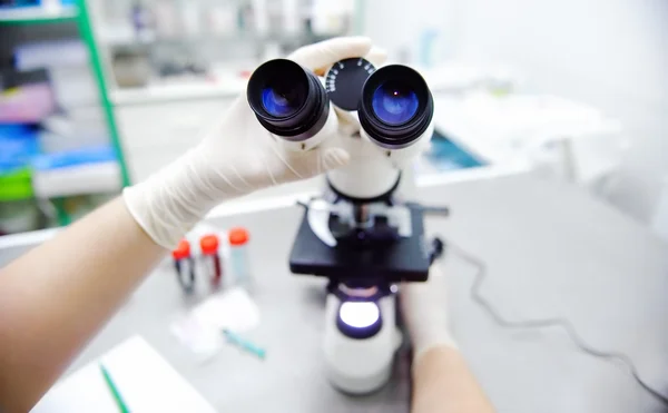 Κοντινή φωτογραφία των χεριών επιστήμονας με μικροσκόπιο, εξέταση δειγμάτων και υγρό — Φωτογραφία Αρχείου