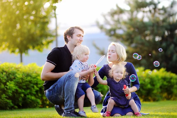 Familia joven con sus hijos pequeños soplando burbujas de jabón —  Fotos de Stock