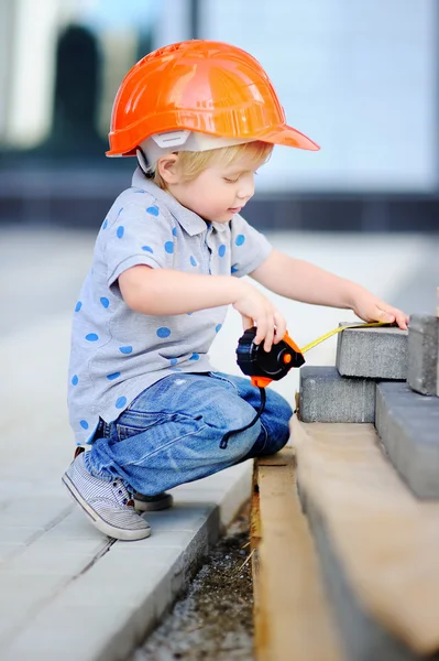 Pequeño constructor en sombreros con regla que trabaja al aire libre — Foto de Stock