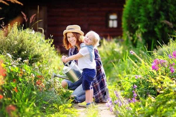 Toddler boy and his mother watering plants in the garden — Stock Photo, Image