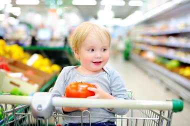 Bir süpermarkette alışveriş sepeti oturuyor ve yürümeye başlayan çocuk