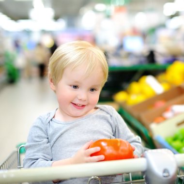 Bir süpermarkette alışveriş sepeti oturuyor ve yürümeye başlayan çocuk