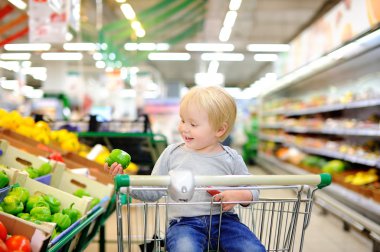 Bir süpermarkette alışveriş sepeti oturuyor ve yürümeye başlayan çocuk