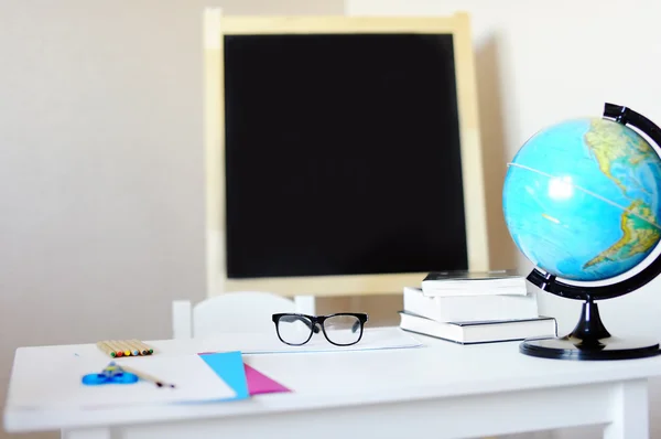 Local de trabalho com escrivaninha escolar, quadro-negro, globo e óculos — Fotografia de Stock