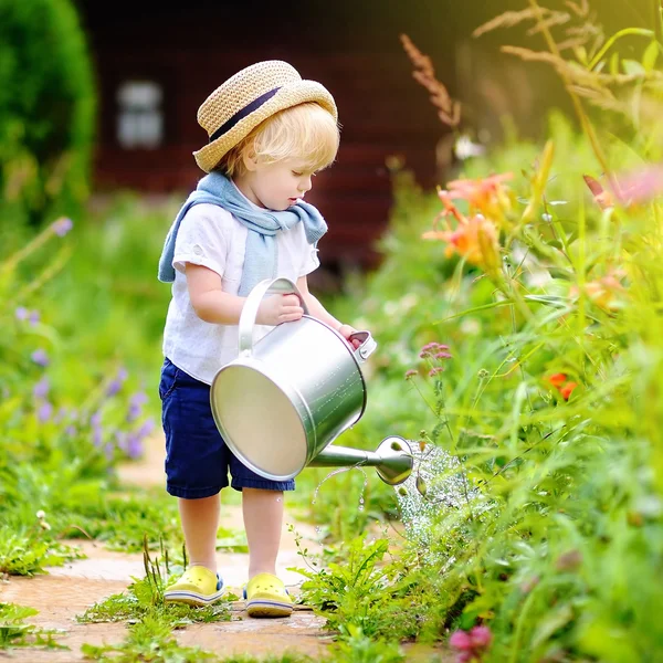 Lindo niño en paja sombrero regar plantas — Foto de Stock