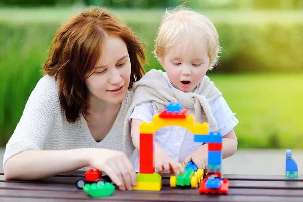 Junge Frau mit Kleinkind spielt mit Plastikklötzen — Stockfoto