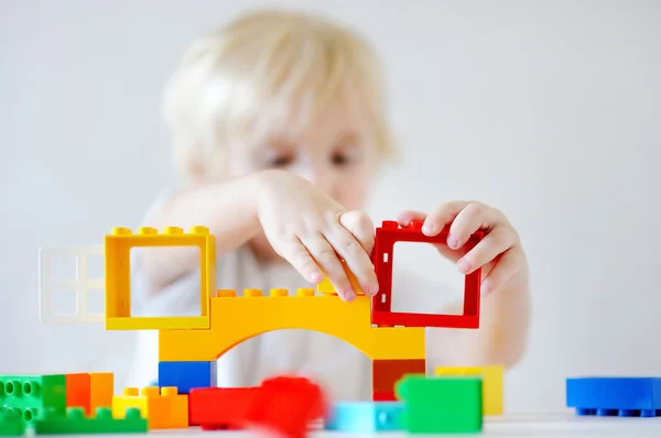 Маленький мальчик играет с пластиковыми блоками, сосредоточиться на руках — стоковое фото