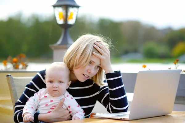 Zmęczony młoda matka pracuje oh jej laptop — Zdjęcie stockowe