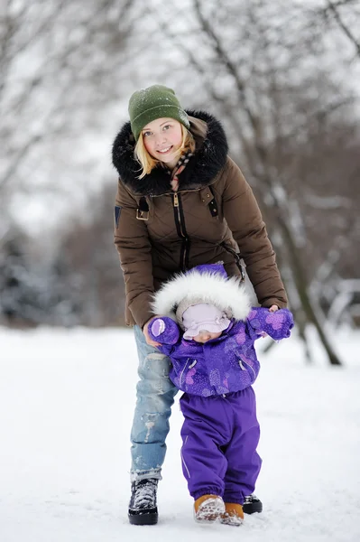 Jonge vrouw met haar peuter meisje in de winter park — Stockfoto