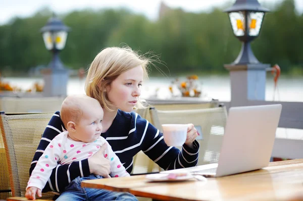 Молода мати з дитиною працює або навчається на ноутбуці — стокове фото