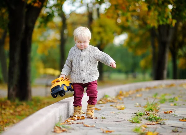 Тодлер грає з іграшковим автомобілем в осінньому парку — стокове фото