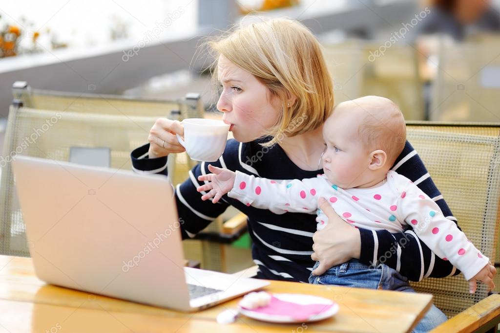 Tired young mother holding 6-month daughter and drinking coffee