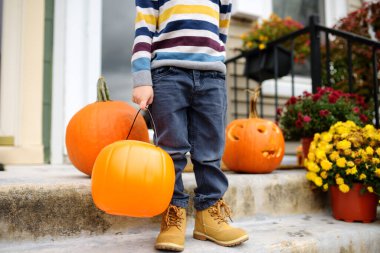 Çocuk şeker mi şaka mı için hazır. Cadılar Bayramı partisindeki küçük çocuk. Çocuk kutlaması Cadılar Bayramı. Geleneksel tatil Bir kova şeker ve şekerle