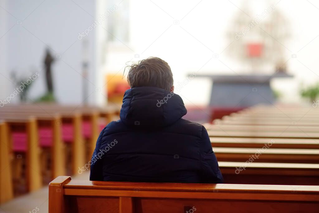 Religious middle age man praying and meditating in catholic church. Person begging for forgiveness and blessing from God. Catholicism is Christianity religion.