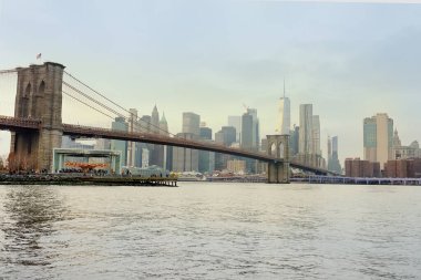 Brooklyn Köprüsü 'nün ve New York' taki Manhattan gökdelenlerinin doğu nehrinin nehir kıyısından kış günbatımında muhteşem bir manzarası var. NYC, ABD 'yi gezmek.