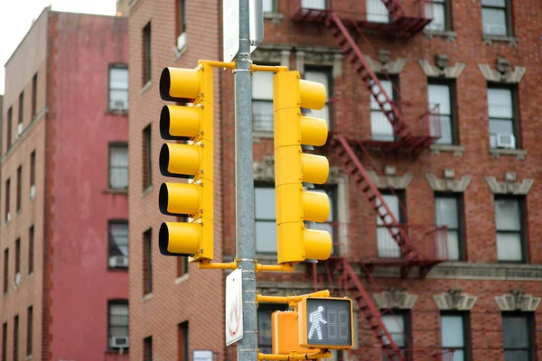 Traditional yellow Traffic Light on background of buildings, Manhattan, New York, USA. Traffic Light is need to control the movement of vehicles and pedestrians on the streets of the city.