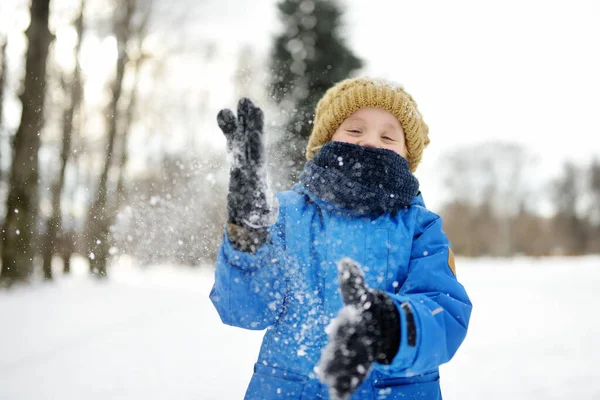 雪の中で新雪と遊ぶのが楽しい男の子 雪合戦だ 暖かい服 手の手袋 スカーフで身を包んだ子供 雪の冬の日に自然の中で子供のためのアクティブな屋外レジャー — ストック写真