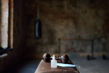 Coronavirus salgını sırasında güvenlik için spor malzemeleri ve koruyucu araçlarla - yüz maskesi ve dezenfektan - boş spor salonu manzarası.