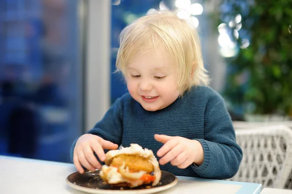ファーストフード店で大きなハンバーガーを食べるかわいい未就学児 子供のための不健康な食事 ジャンクフード 太りすぎの問題の子供 — ストック写真