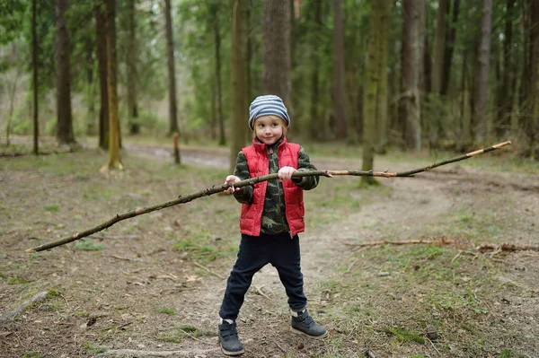 Malý Chlapec Červené Vestě Hraje Velkou Větví Baví Lese Začátku — Stock fotografie