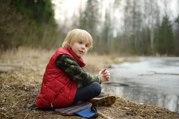 Kleine Jongen Rustend Oever Van Het Bosmeer Vroege Lente Buitenactiviteiten — Stockfoto