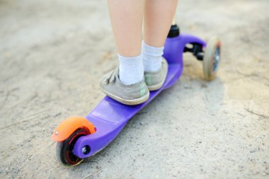 Bebek, scooter sürmeyi öğreniyor. Çocuk ayağı yakın. Çocuklar için yaz sporu yaşam tarzı ve eğlence.