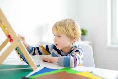 İlkokul öğrencisi evde ödev yapıyor. Çocuk saymayı öğreniyor, aritmetik örnekler çözüyor, çalışma kitabı alıştırmaları yapıyor. Matematik dersi. Anaokulu bebeğini okula hazırlamak. Çocuklar için eğitim.