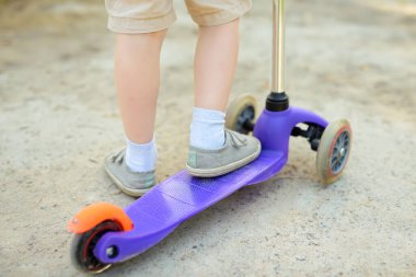 Bebek, scooter sürmeyi öğreniyor. Çocuk ayağı yakın. Çocuklar için yaz sporu yaşam tarzı ve eğlence.