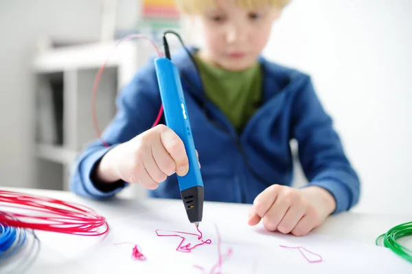 Little boy learning make model with 3d printing pen. Child playing with new toy for creativity. DIY. STEM and STEAM education. Modern technologies.