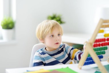 İlkokul öğrencisi evde ödev yapıyor. Çocuk saymayı öğreniyor, aritmetik örnekler çözüyor, çalışma kitabı alıştırmaları yapıyor. Matematik dersi. Anaokulu bebeğini okula hazırlamak. Çocuklar için eğitim.