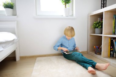 Preschooler boy playing pc game by tablet. Overuse and addiction kids from gadgets. Digital device addiction.