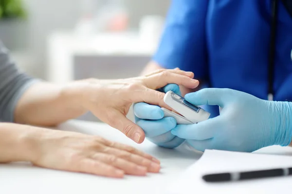 A woman at a doctor\'s appointment during the coronavirus epidemic. Doctor checking oxygenation with fingertip pulse oximeter. Saturation blood of oxygen.